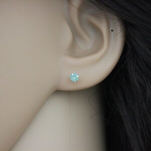 May include: A pair of small, round, light blue stud earrings. The earrings are set in silver.