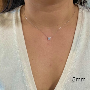 May include: A silver chain necklace with a small, round, clear gemstone pendant. The pendant is 5mm in diameter.