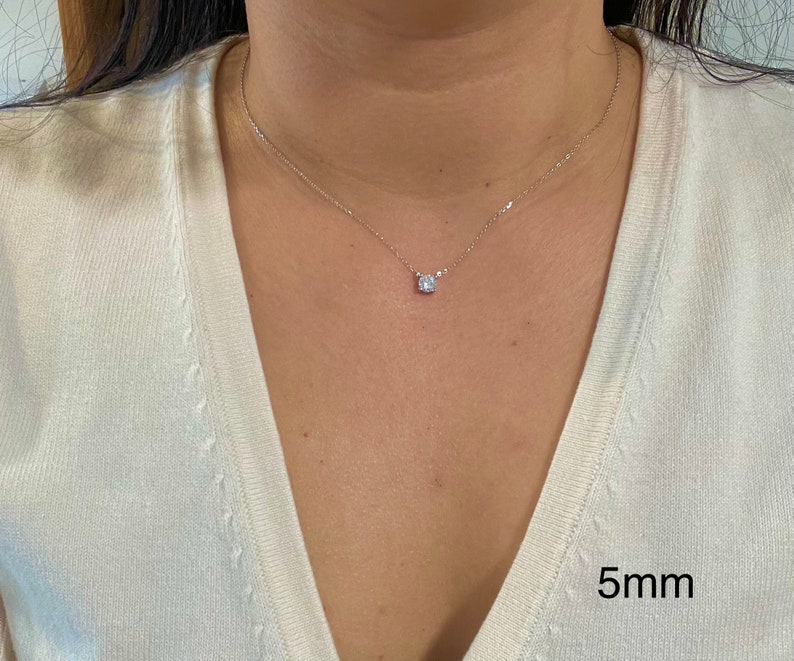 May include: A silver chain necklace with a small, round, clear gemstone pendant. The pendant is 5mm in diameter.