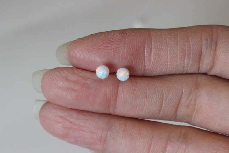 May include: A pair of small, round, white opal stud earrings. The earrings are set in silver.