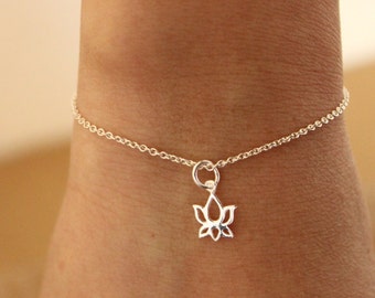 May include: A delicate silver chain bracelet featuring a lotus flower charm. The chain is thin and delicate, and the charm is a simple, elegant design.