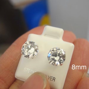 Puede incluir: Un par de pendientes de plata de ley con piedras de circonita c&uacute;bica transparentes de 8 mm.