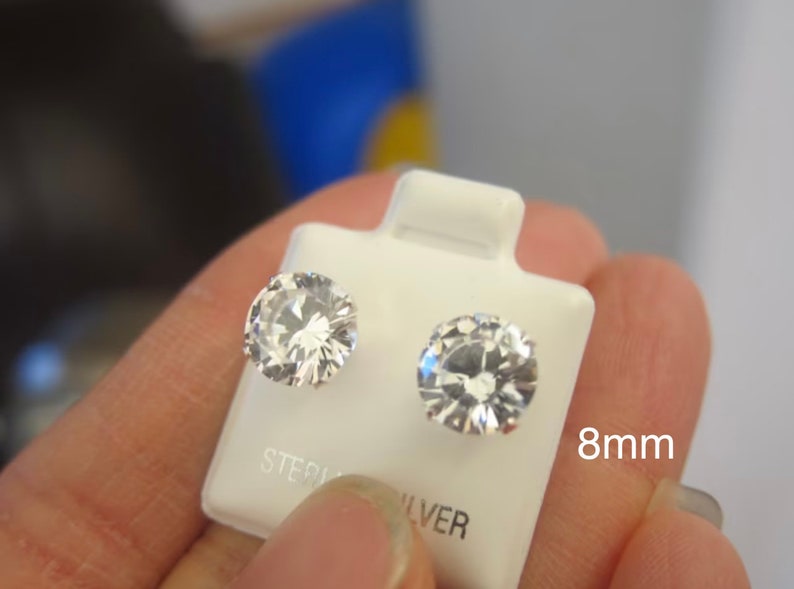 Puede incluir: Un par de pendientes de plata de ley con piedras de circonita c&uacute;bica transparentes de 8 mm.