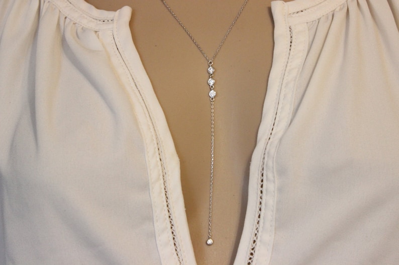 May include: A long silver chain necklace with four small clear cubic zirconia stones.