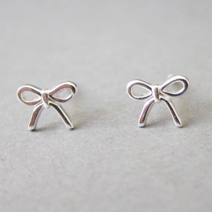 May include: A pair of silver bow-shaped stud earrings.