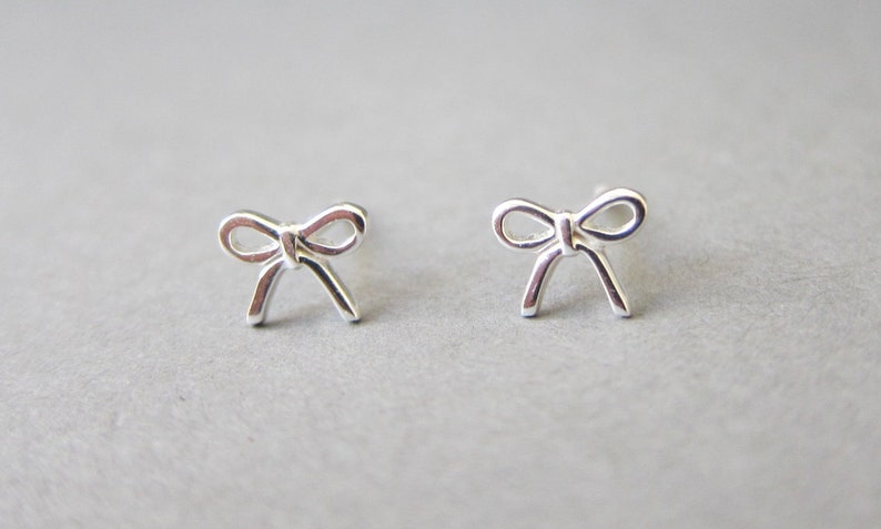 May include: A pair of silver bow-shaped stud earrings.