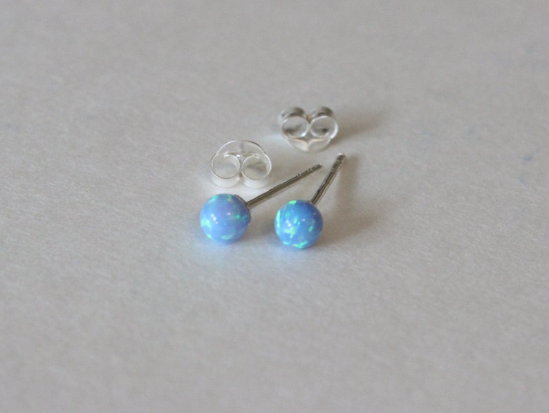 May include: A pair of silver stud earrings with blue opal stones.