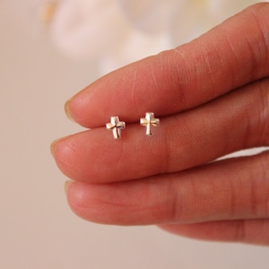 May include: A pair of silver cross stud earrings. The earrings are small and delicate, and they are perfect for everyday wear.