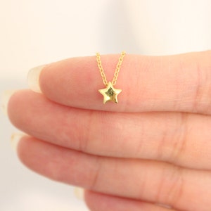 May include: A delicate gold chain necklace with a small, star-shaped pendant.