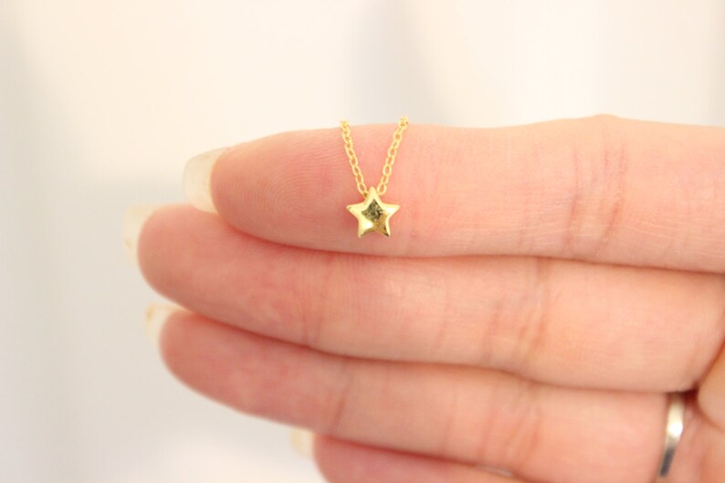 May include: A delicate gold chain necklace with a small, star-shaped pendant.