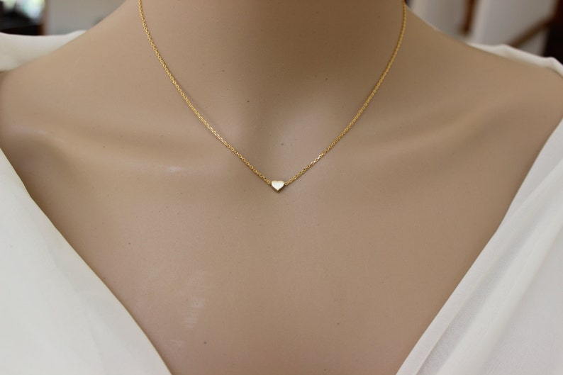 K&ouml;nnte beinhalten: Eine zarte goldene Kettenkette mit einem kleinen, flachen Herzanh&auml;nger.