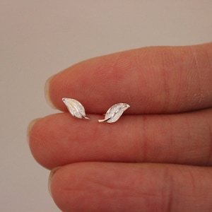 以下が含まれることがあります： 銀の葉の形をしたイヤリングのペア。イヤリングは小さく繊細で、毎日の着用に最適です。