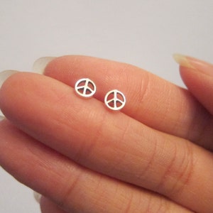 Op de afbeelding: Een paar zilveren oorbelletjes met een peace-teken. De oorbelletjes zijn klein en delicaat en perfect voor dagelijks gebruik.