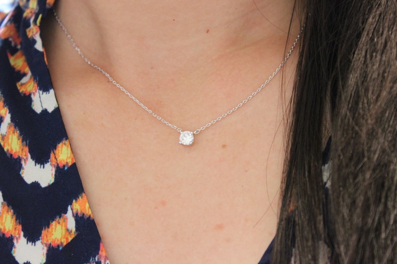 May include: A simple silver chain necklace with a single, clear, round gemstone pendant.