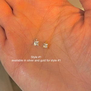 May include: Two small square-cut gemstone pendants, one silver and one gold, are displayed. The image includes text that reads "Style #1 available in silver and gold for style #1."