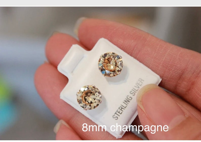 Puede incluir: Un par de pendientes de bot&oacute;n de color champ&aacute;n de 8 mm en una tarjeta blanca con el texto "Sterling Silver".