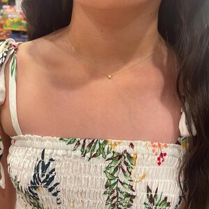 May include: A delicate gold chain necklace with a small, clear gemstone pendant.