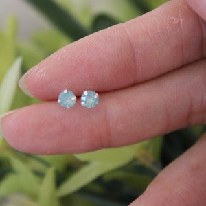 May include: A pair of silver stud earrings with light blue round gemstones.