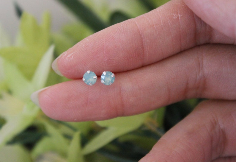 May include: A pair of silver stud earrings with light blue round gemstones.