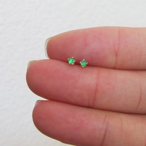 May include: A pair of small, silver stud earrings with green gemstones.