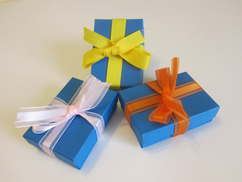 May include: Three blue gift boxes with different colored ribbon bows. The boxes are tied with yellow, pink, and orange ribbon.