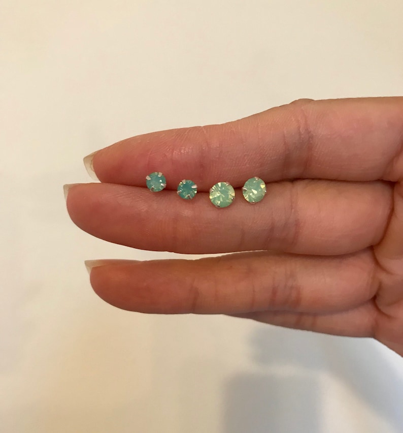 May include: Four pairs of small, round, light green opal stud earrings.