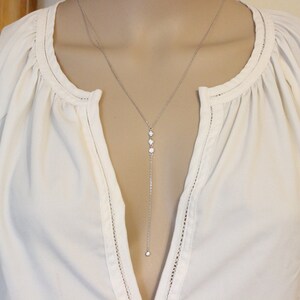 May include: A silver chain necklace with three small round stones and a larger stone at the bottom.
