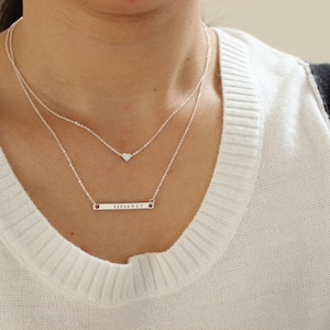 K&ouml;nnte beinhalten: Eine silberne Halskette mit einem kleinen Herz-Anh&auml;nger und einem l&auml;ngeren Barren-Anh&auml;nger mit der Gravur "perfekt".