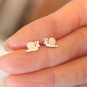 May include: A pair of silver snail stud earrings. The snails are facing the same direction and have a detailed shell design.