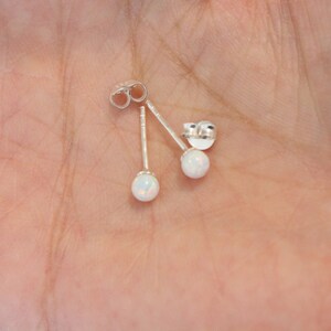 May include: A pair of silver stud earrings with white opal stones.