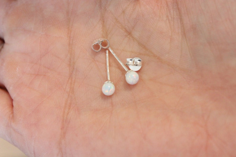 May include: A pair of silver stud earrings with white opal stones.