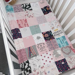 May include: A pink and white patchwork baby quilt with various designs and text, including "Daddy's Princess", "Born in 2019", and "For Amazing".
