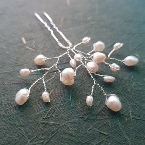 Puede incluir: Un peine para el cabello delicado con una base de alambre plateado y múltiples acentos de perlas. Las perlas están dispuestas en cascada, creando un aspecto caprichoso y elegante.