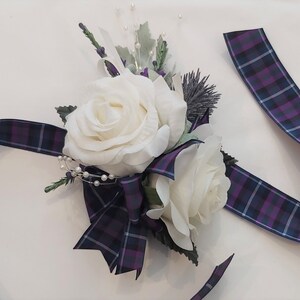 Puede incluir: Un brazalete de novia de rosa blanca con una cinta de cuadros morado y azul.