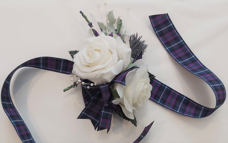 Puede incluir: Un brazalete de novia de rosa blanca con una cinta de cuadros morado y azul.