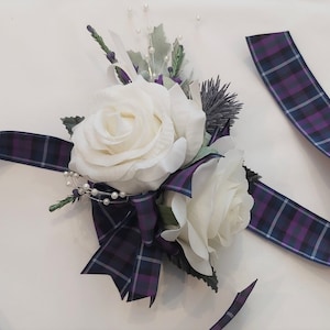 Puede incluir: Un brazalete de novia de rosa blanca con una cinta de cuadros morado y azul.
