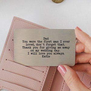 May include: A pink leather wallet with a silver metal card inside. The card has a message engraved on it that reads: "Dad You were the first man I ever loved, don't forget that. Thank you for giving me away on my wedding day. I will love you always. Katie"