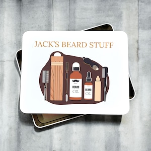 May include: A white tin with the text "JACK'S BEARD STUFF" on the lid. The tin contains a variety of beard care products, including beard oil, combs, and a wooden beard brush.