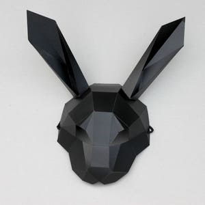 Puede incluir: Una m&aacute;scara de conejo geom&eacute;trica negra con un dise&ntilde;o triangular. La m&aacute;scara tiene una superficie plana y est&aacute; hecha de un material r&iacute;gido.
