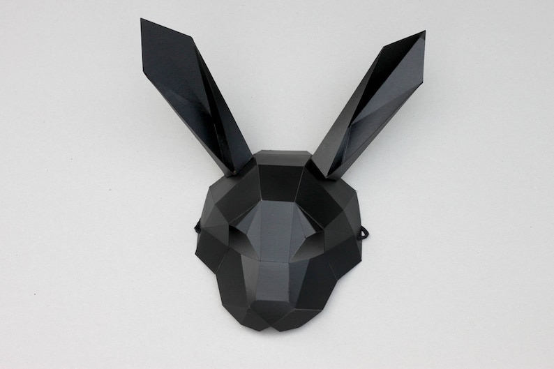 Puede incluir: Una m&aacute;scara de conejo geom&eacute;trica negra con un dise&ntilde;o triangular. La m&aacute;scara tiene una superficie plana y est&aacute; hecha de un material r&iacute;gido.