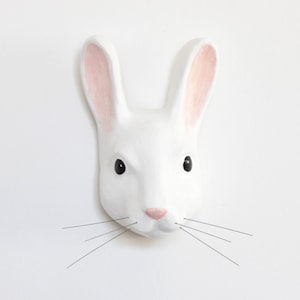 May include: White ceramic rabbit head wall decor with pink ears and black eyes.