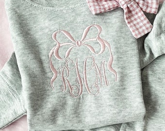 May include: A gray two-piece baby outfit with a pink bow and monogrammed with the letters "RHM".