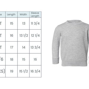 K&ouml;nnte beinhalten: Eine Gr&ouml;&szlig;entabelle f&uuml;r ein graues Langarmshirt f&uuml;r Kleinkinder und junge Kinder. Die Tabelle zeigt die Gr&ouml;&szlig;e, L&auml;nge, Breite und &Auml;rmell&auml;nge in Zoll. Die Gr&ouml;&szlig;en umfassen 2T, 3T, 4T, 5/6 und 7(XS).