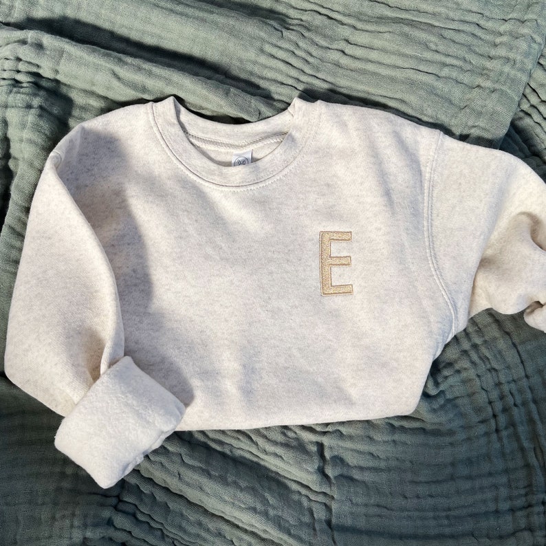 heather oatmeal toddler crew with single embroidered block initial on the left chest in camel thread