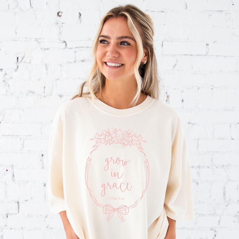 girl wearing an ivory comfort colors t-shirt with custom grow in grace floral frame printed design