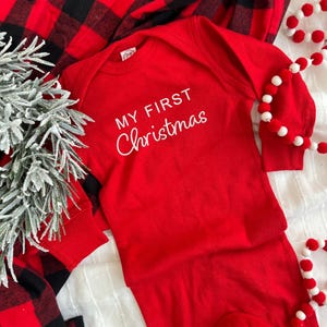 May include: Red long-sleeve onesie with white text that reads "My First Christmas".