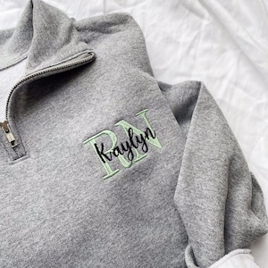 May include: Grey sweatshirt with a zip and a green embroidered design that says "RN Kaylyn".