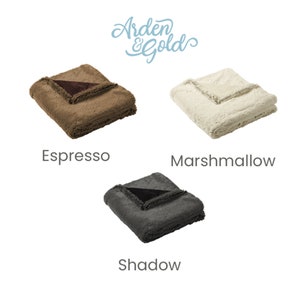 Pu&ograve; includere: Tre coperte di peluche piegate in Espresso, Marshmallow e Shadow. Ogni coperta ha un bordo a contrasto. Il logo Arden & Gold &egrave; in alto a destra.