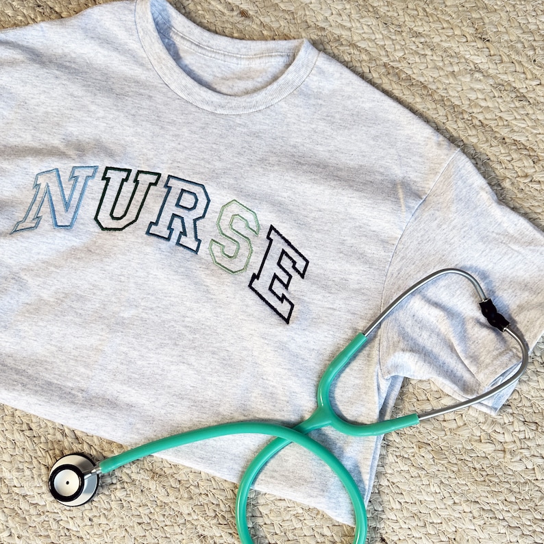 an ash crewneck tee with custom NURSE embroidered design in shades of blue and green