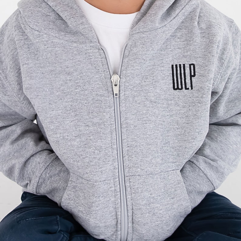 toddler boy wearing a full zip hooded heather grey sweatshirt with embroidered monogram on the left chest